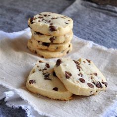 chocolate chip cookies sitting on top of a white towel next to a glass of milk