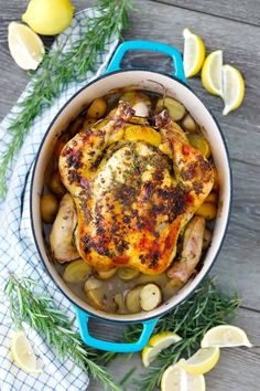 a chicken in a pot with lemons and rosemary garnish on the side