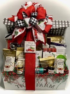 a christmas gift basket with wine, cheeses and crackers in red ribbon tied around it