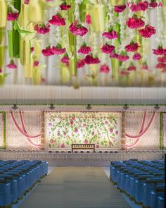 the interior of a church with rows of blue chairs and flowers hanging from the ceiling