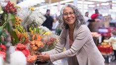 an older woman is shopping for flowers in the store and she is smiling at the camera