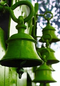 several green bells hanging from the side of a building