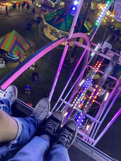 a person is sitting on a ferris wheel looking down at the fairground and carnival rides