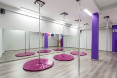 an empty gym with pink and purple exercise mats on the floor in front of mirrors