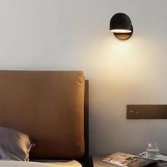 a bed with a lamp on the wall above it