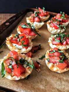 small appetizers with tomatoes and spinach are on a baking sheet, ready to be eaten