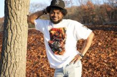 a man standing next to a tree wearing a hat