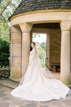 a woman in a wedding dress is posing for the camera with her veil pulled back