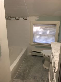 a bathroom with a toilet, sink and bathtub in it next to a window