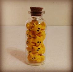 a glass bottle filled with yellow candies on top of a table