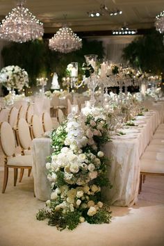 the table is set with white flowers and crystal chandeliers