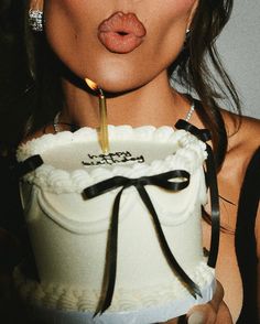 a woman sticking her tongue out while holding a cake with a lit candle in it