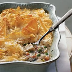 a casserole dish with chicken and vegetables in it on a white plate next to a fork