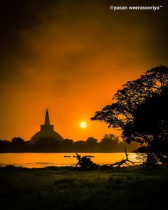 the sun is setting over an island with a church in the distance and trees on the shore