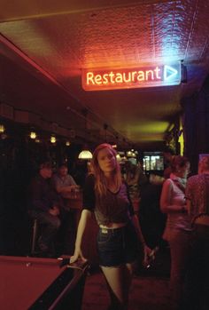 a woman standing next to a pool table