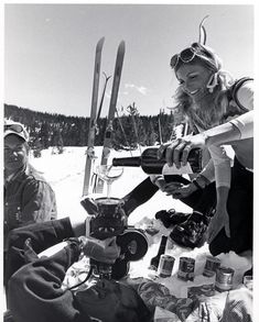 a group of people sitting on top of a snow covered ground next to skis