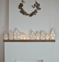 a fireplace mantle with lit candles in the shape of houses