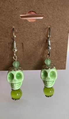 1 3/4"Long Dangling hook beaded earrings are made with ceramic  light green skulls, cat's eye beads, glass beads & antiqued silver accent beads. The earring hooks are sterling silver plated. Great pair of festive Halloween earrings to add to any collection.                             Hand crafted by myself in the U.S.A.                                      Thank you for looking                                       Have a awesome day! Halloween Earring Ideas, Green Beaded Pierced Earrings, Green Novelty Earrings For Halloween, Green Novelty Jewelry For Halloween, Adjustable Jade Beaded Earrings As A Gift, Adjustable Jade Beaded Dangle Earrings, Green Novelty Dangle Earrings, Green Dangle Novelty Jewelry, Green Novelty Dangle Jewelry