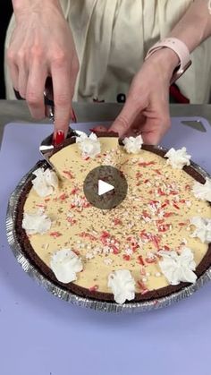 a person cutting into a pie on top of a blue tablecloth with white and red sprinkles