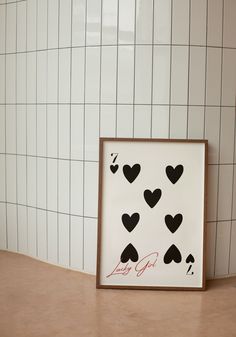 a white tile wall with black hearts on it and a wooden frame in the middle