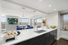 a kitchen with white counter tops and gray cabinets next to a large window overlooking the city