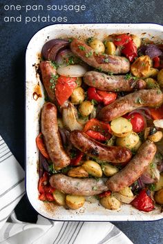 a casserole dish with sausages, potatoes and tomatoes