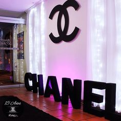 the word chanel is lit up in front of a window with curtains and lights