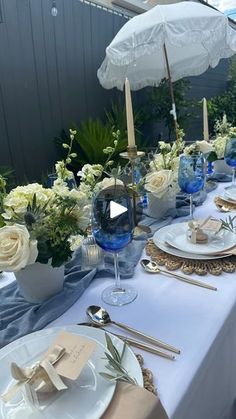 the table is set with blue and white plates, silverware, napkins, and an umbrella