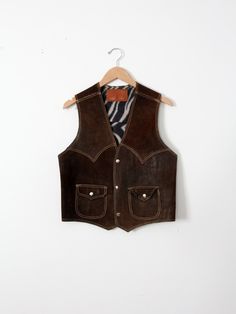 "This is a 1970s vintage suede leather vest. Dark brown suede shapes the vest with tan top-stitching. It features snap pockets on the waist, and snaps closed. The interior has a zebra print lining. CONDITION In good condition with wear consistent with age and use. Fantastic natural wear and patina to the leather. Approximate Size: Men's Small / Medium  MEASUREMENTS Bust:           38\"  ...         96.5 cm Length:       20\"      ...          50.8 cm Shoulders: 13.5\"      ...        34.3 cm HOW Cowboy Vest, Leather Biker Vest, Looks Country, Brown Vest, Biker Vest, Suede Vest, Men Suede, Tan Top, Vintage Vest