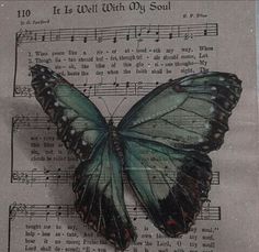 a blue butterfly sitting on top of sheet music