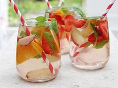 three glasses filled with different types of fruit and drink garnished with straws