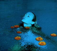 a woman floating in the water surrounded by flowers