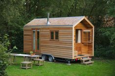 a small wooden house sitting on top of a lush green field next to a picnic table