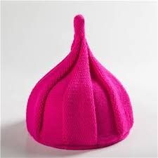 a bright pink knitted beanie sitting on top of a white table