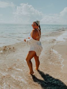 a woman in a white dress is running on the beach