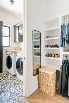 a washer and dryer in a room with clothes hanging on the shelves next to it