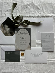 the wedding stationery is laid out neatly on top of the bed sheet and tied with a green ribbon