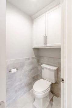 a white toilet sitting inside of a bathroom next to a wall mounted towel dispenser