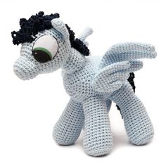 a small crocheted pony with big eyes and black hair is posed on a white background