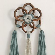 a decorative wall hanging with tassels and wood circles on the top, along with two smaller tassels attached to it