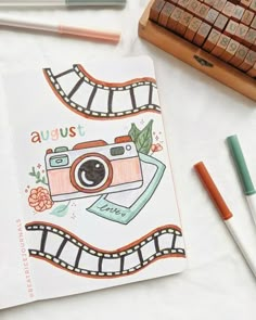 a notebook with an image of a camera on it next to some markers and pencils