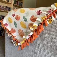 an orange and white fall themed blanket on a couch with bookshelves in the background