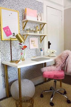 a pink chair sitting in front of a white desk with gold legs and shelves on the wall