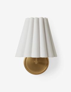 a gold wall light with a white shade on it