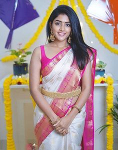 a woman in a white and pink saree standing next to a table with decorations on it