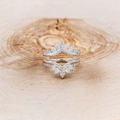 two wedding rings sitting on top of a tree stump in front of a wooden background