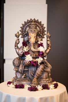 a statue of the god ganesh is on top of a table with flowers around it