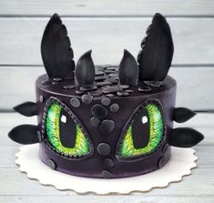 a cake decorated with black icing and green eyes