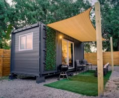 a tiny house made out of shipping containers in the backyard with grass and trees surrounding it