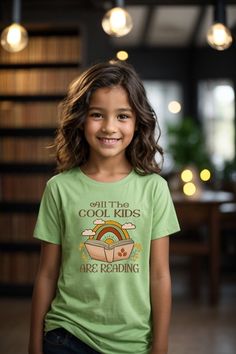 Kids Reader T-Shirt The kids heavy cotton tee is perfect for everyday use.  The fabric is 100% cotton for solid colors. Polyester is included for heather-color variants.  These fabrics are prime materials for printing.  The shoulders have twill tape for improved durability. The collar is curl resistant due to ribbed knitting.  There are no seams along the sides.  .: Material: 100% cotton (fiber content may vary for different colors) .: Midweight fabric (5.3 oz/yd² (180 g/m .: Classic fit .: Tear-away label .: Runs true to size SIZING: Runs true to size, but please refer to size chart, to order according to your exact measurements. Sweatshirt https://moonlitwonderland.etsy.com/listing/1614431226 Sweatshirt https://moonlitwonderland.etsy.com/listing/1582559870 Sweatshirt https://moonlitwonde Kids Reading, Kids Tops, Twill Tape, Color Choices, Cotton Fiber, Cool Kids, Color Matching, Heavy Cotton, Cotton Tee